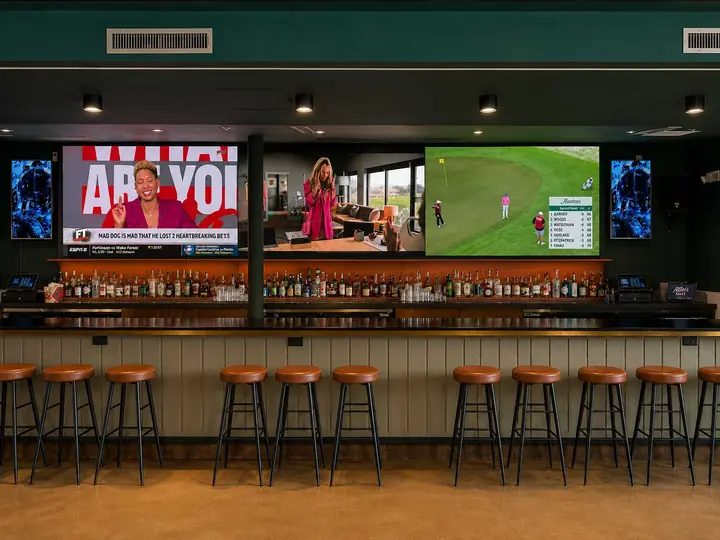 Atlee's Rally back bar with video screens and a row of leather bar stools
