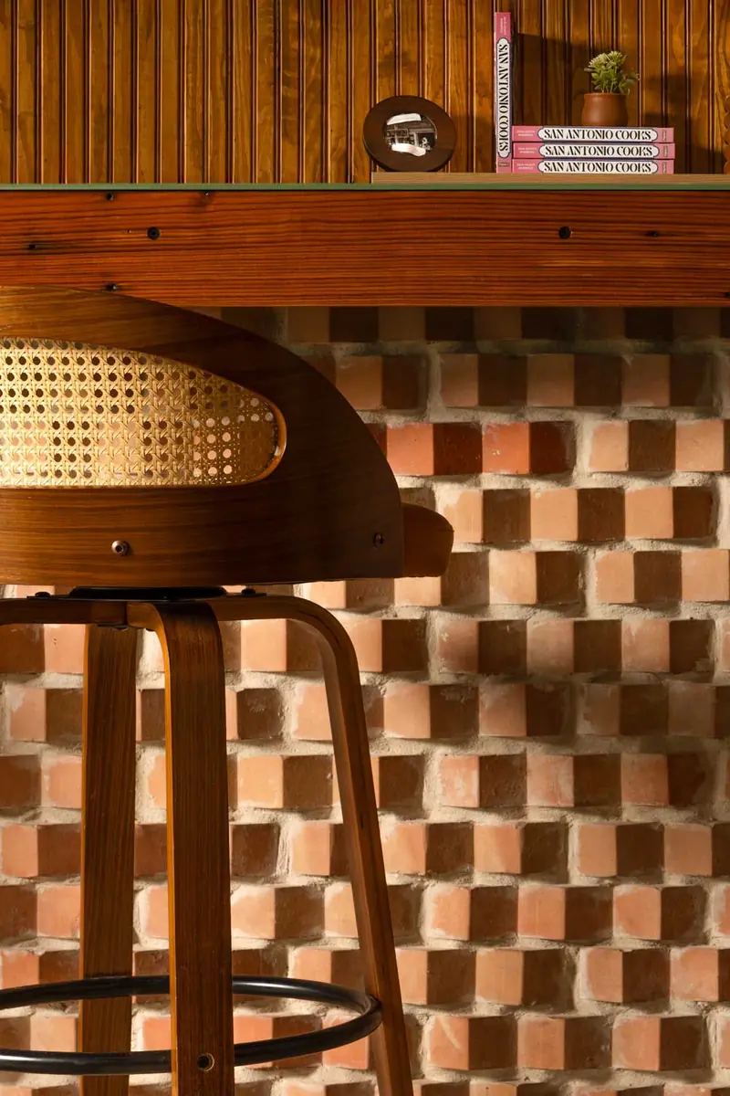 Wood bar stool with cane back and checkerboard brick bar front at South BBQ