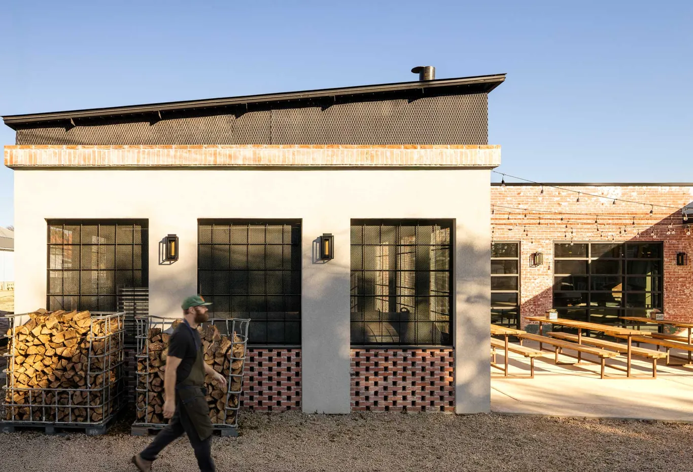 South BBQ restaurant exterior in San Antonio with black steel-frame windows, firewood racks and patio seating
